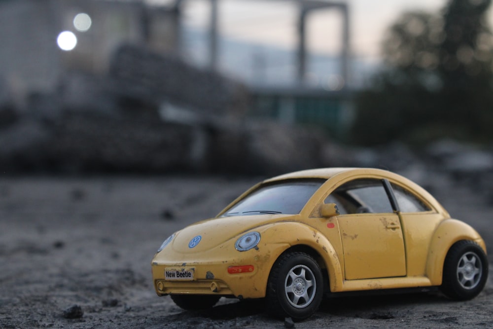 a yellow toy car sitting on top of a dirt field