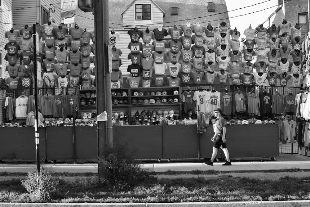 a black and white photo of a person walking past a store