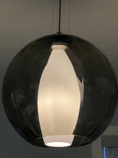 A brutalist-modern style pendant lamp made from stacked glass blocks hanging over a wooden table