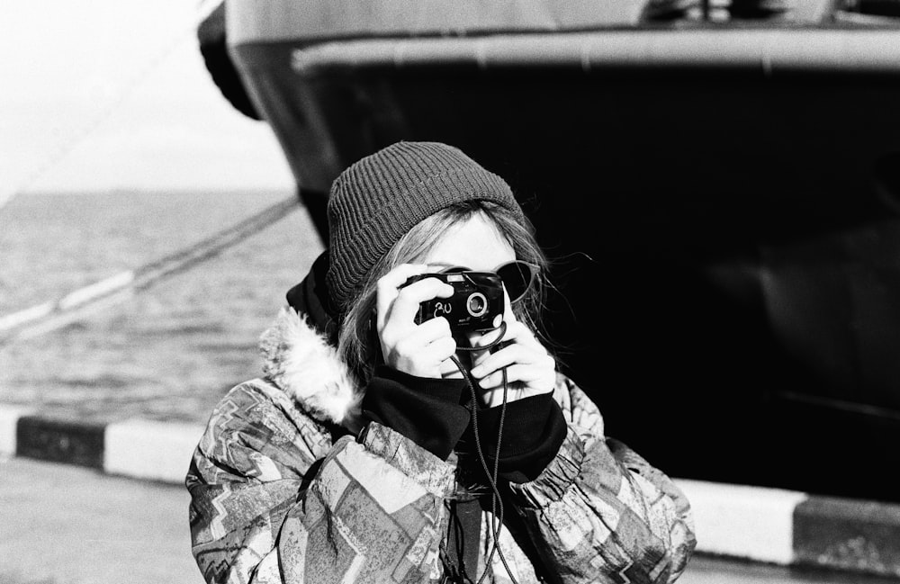 a woman taking a picture of a boat with a camera