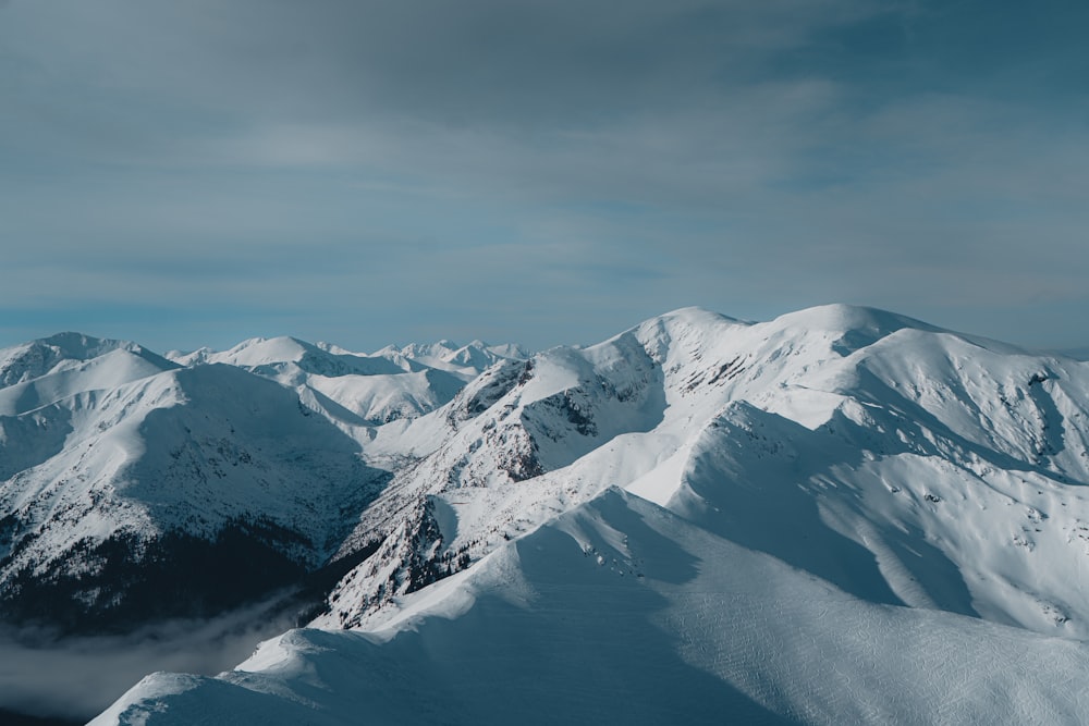 a mountain range covered in snow under a cloudy sky