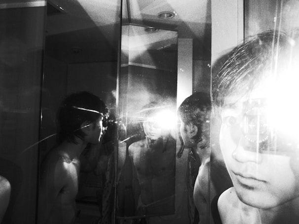 A dimly lit photo of a cracked mirror reflecting a blurred face, symbolizing fractured identity.