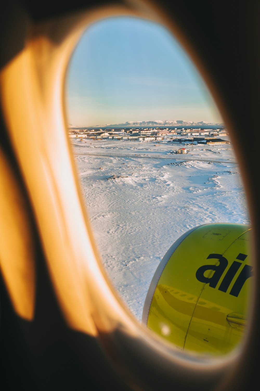a view out of an airplane window of a snowy landscape