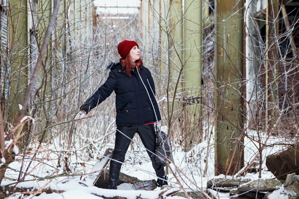 a woman in a red hat is walking through the woods