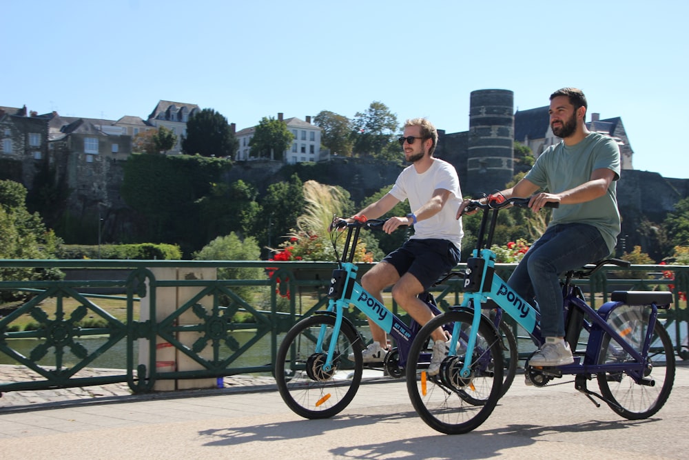 Un par de hombres montando en bicicleta a través de un puente