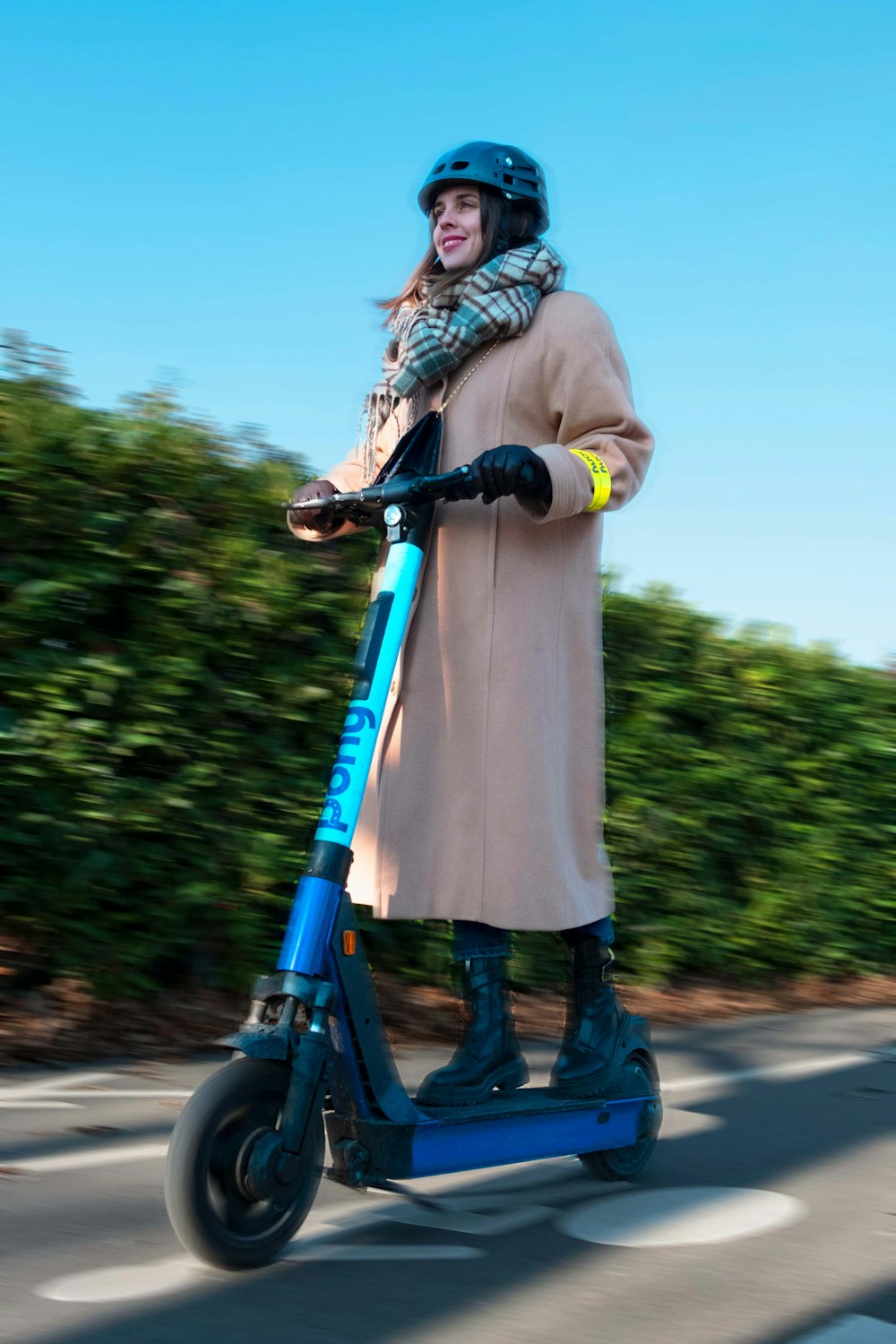 a woman riding a blue scooter down a street