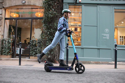 Rider wearing helmet cruising on an electric scooter along a riverside promenade.