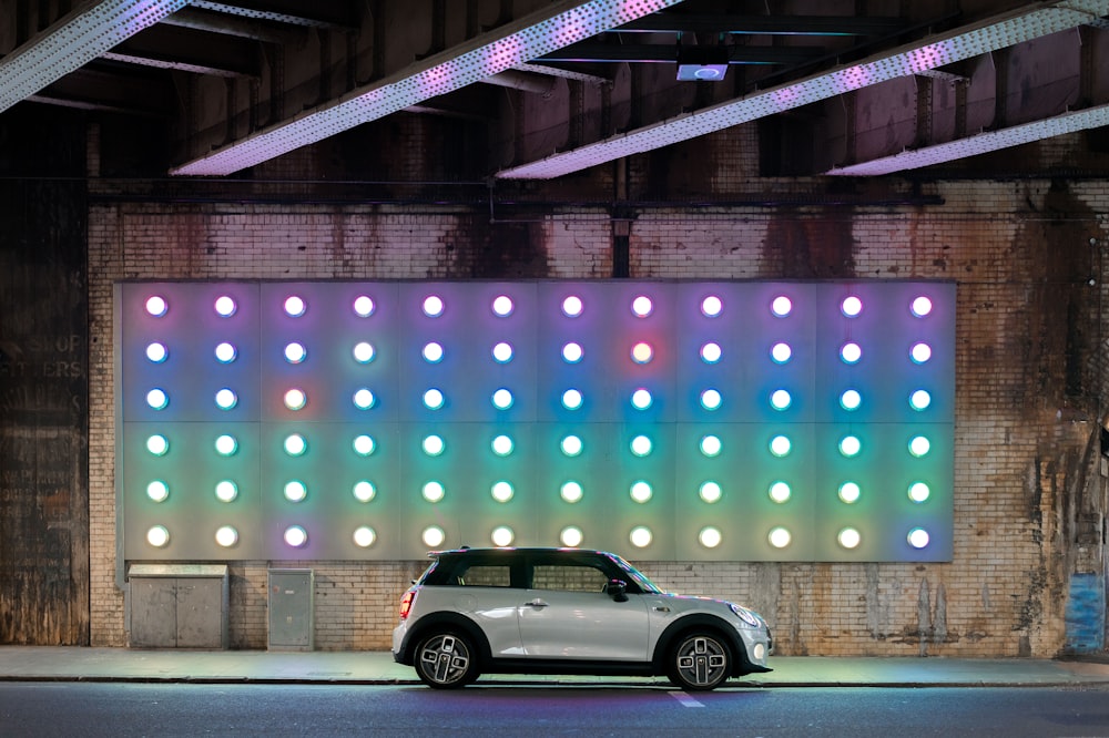 a mini car parked in front of a wall with colorful lights