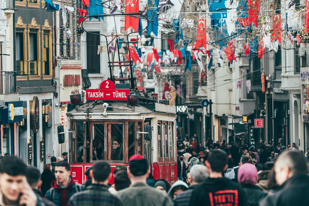 a crowd of people walking down a street next to a cable car