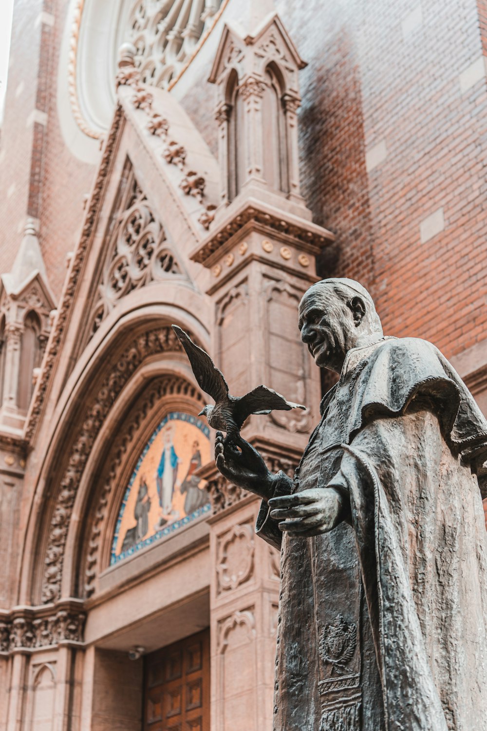 a statue of a man holding a bird in front of a church