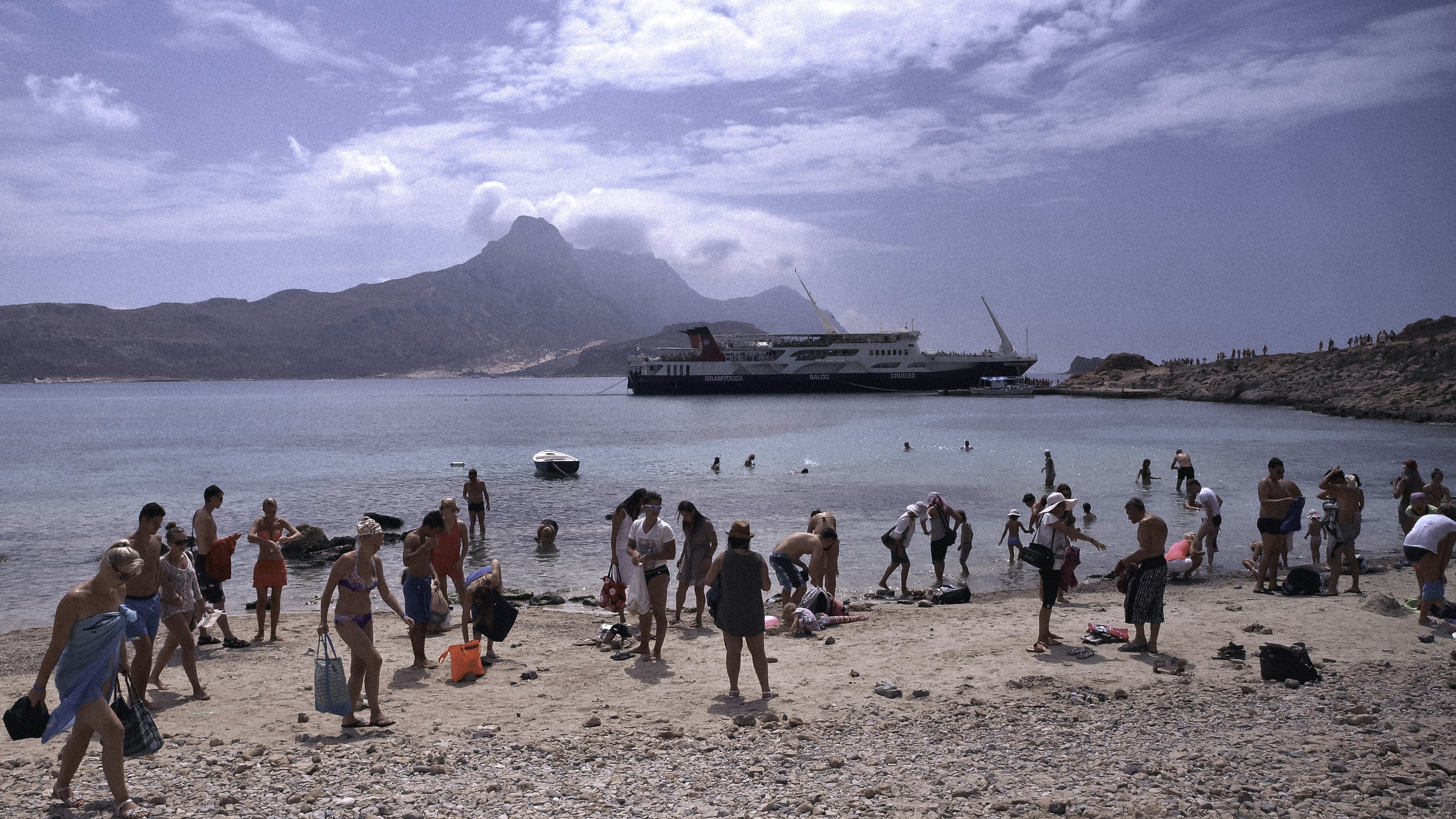 a group of people standing on a beach next to a body of water