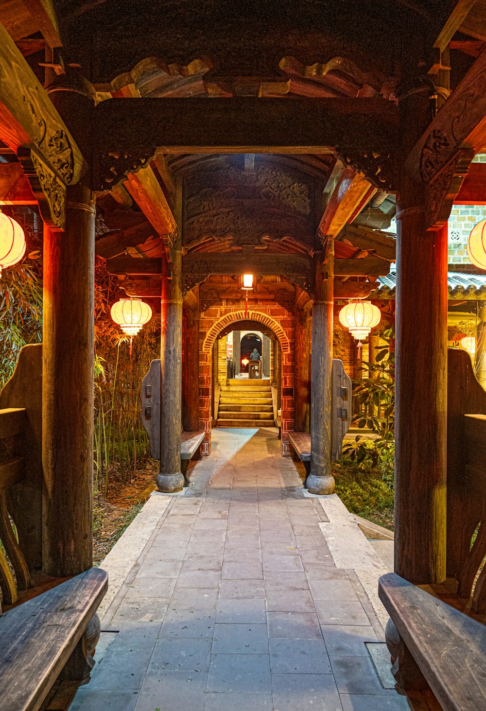a walkway lined with wooden benches and lanterns
