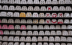 Concrete blocks with holes are stacked in neat rows, with some faces featuring hand-drawn smiley faces and words in bright colors such as yellow, orange, and red.
