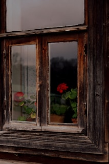Close-up of original wooden window frames with peeling paint, highlighting the house’s aged charm.