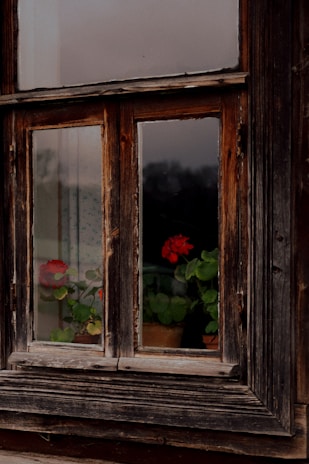 Close-up of original wooden window frames with peeling paint, highlighting the house’s aged charm.