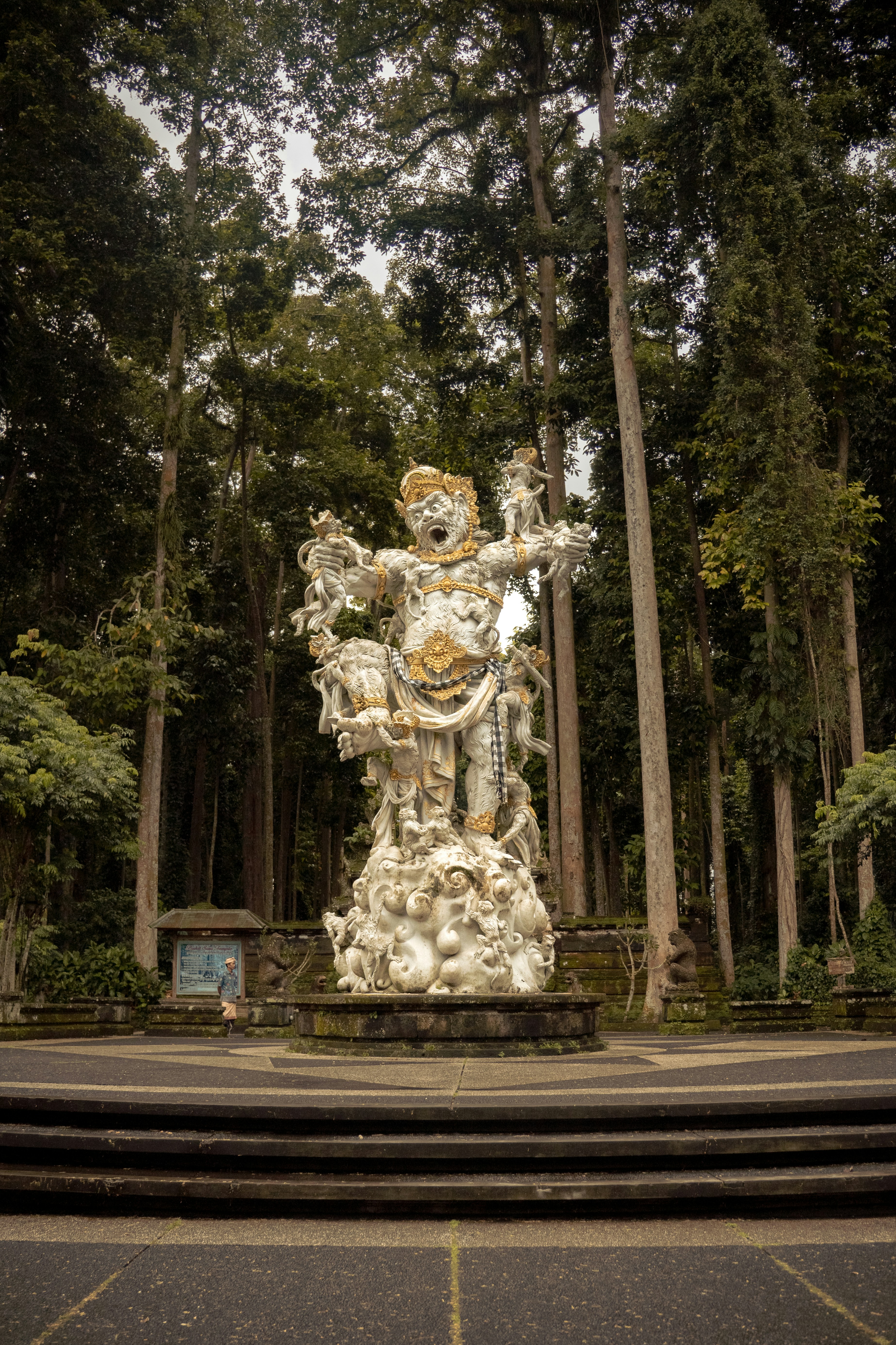 a statue in the middle of a park surrounded by trees