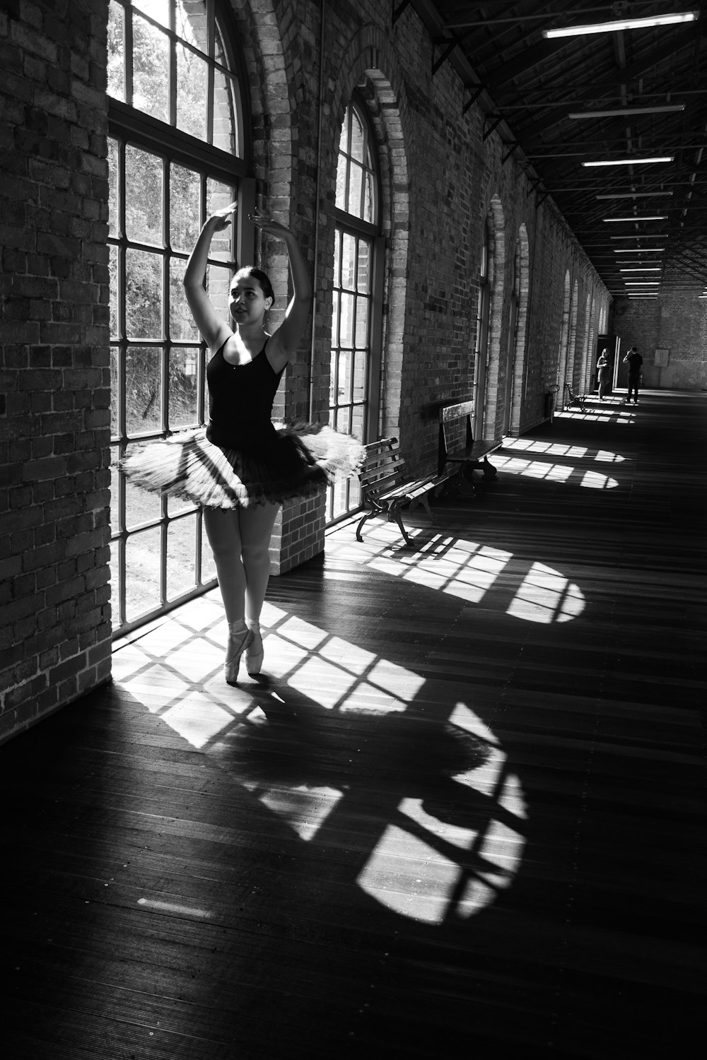 a ballerina in a black leotard is posing in front of a window