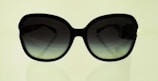 A pair of sunglasses with a reflective lens against a neutral backdrop.