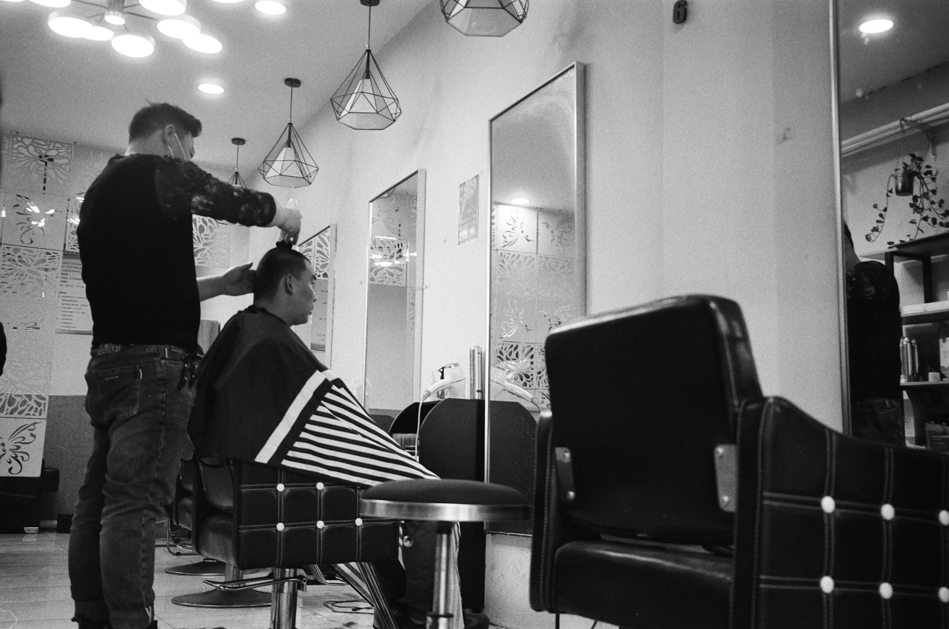 a black and white photo of a barber cutting a customer's hair