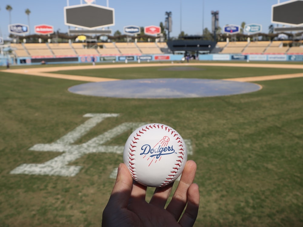 a person holding a baseball in front of a baseball field