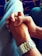 Two hands are clasped together in a gesture of unity or partnership. One person wears a silver metal watch on their wrist. The background includes the seat of a vehicle with a blue fabric and yellow patterns.