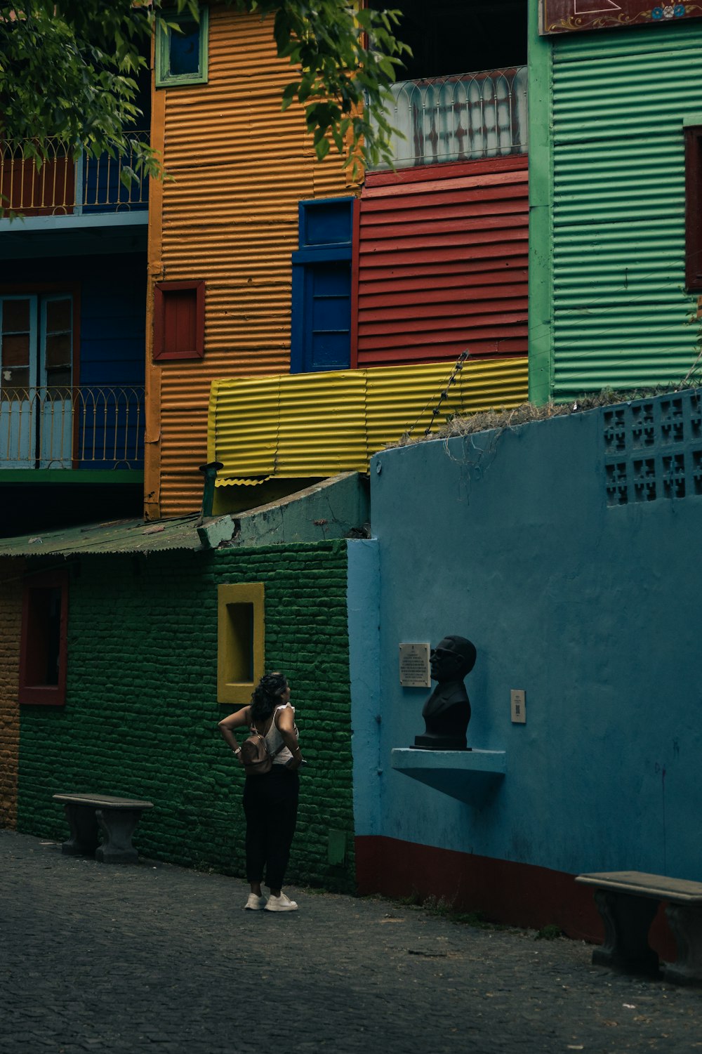 uma mulher em pé na frente de um edifício multicolorido