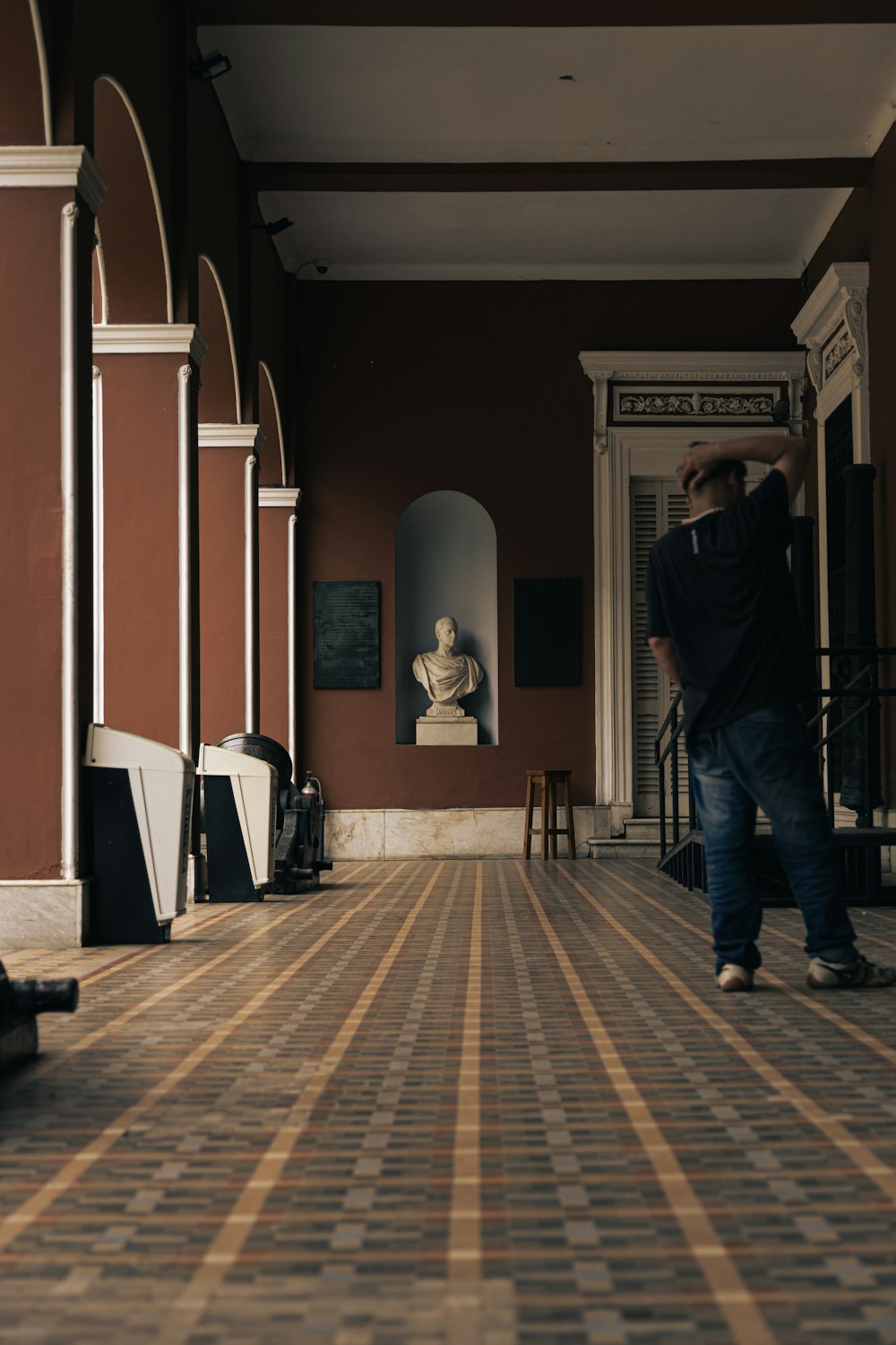 a man walking down a hallway next to a statue