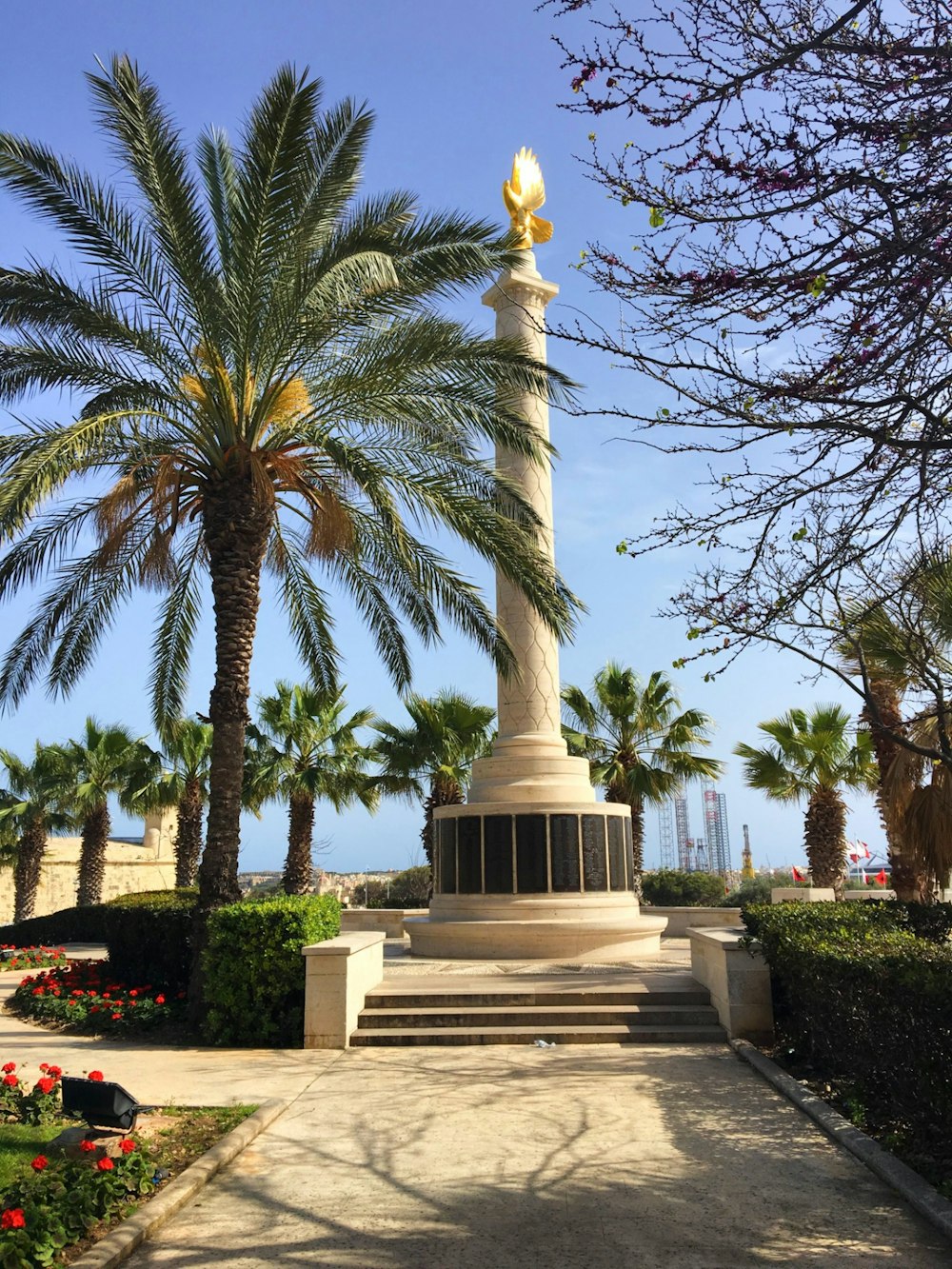 a large white monument with a golden top surrounded by palm trees