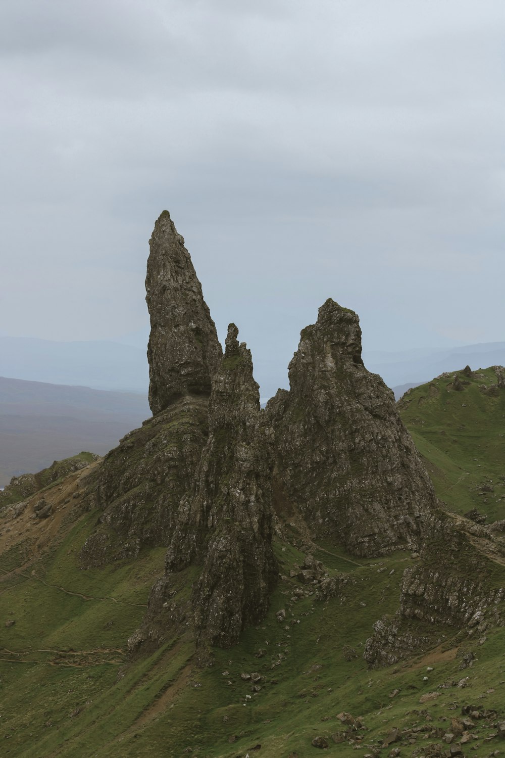 a large rock formation sitting on top of a lush green hillside