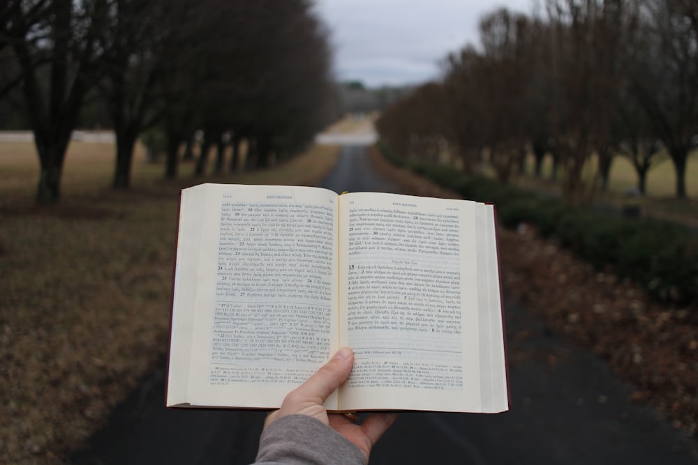 a person holding an open book in their hand