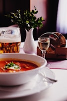 A wooden table set with plates of rustic food and glasses of craft beer, sunlight streaming through windows.