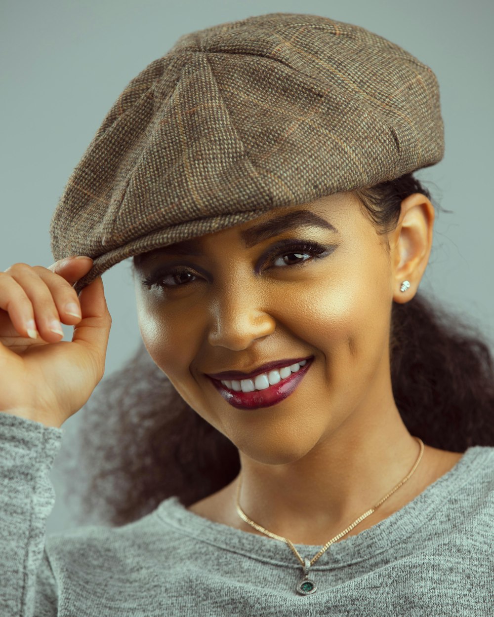 uma mulher usando um chapéu e sorrindo para a câmera