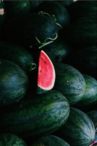 a pile of watermelon with a slice cut out of it