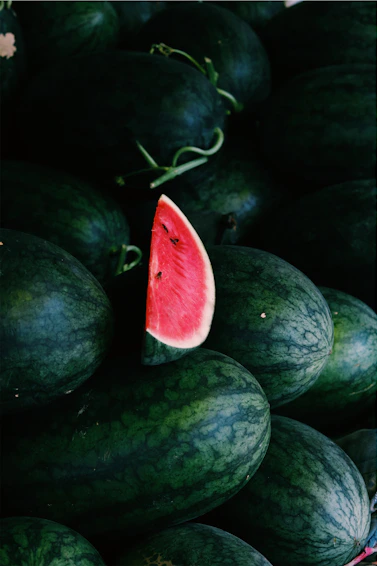 a pile of watermelon with a slice cut out of it