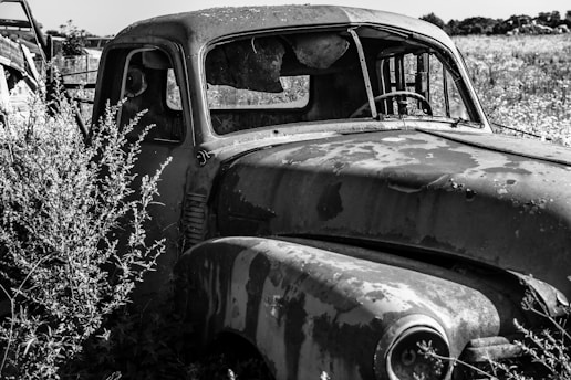 a black and white photo of an old truck in a field