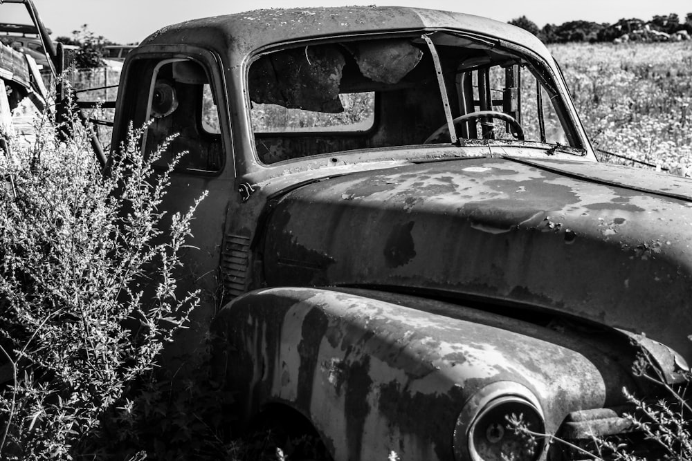 a black and white photo of an old truck in a field