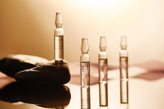 a hand holding a bottle of liquid next to a row of bottles