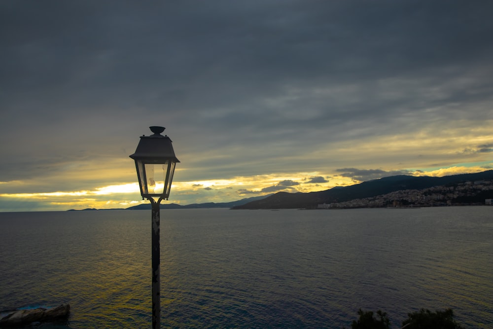 a street light on a pole in front of a body of water