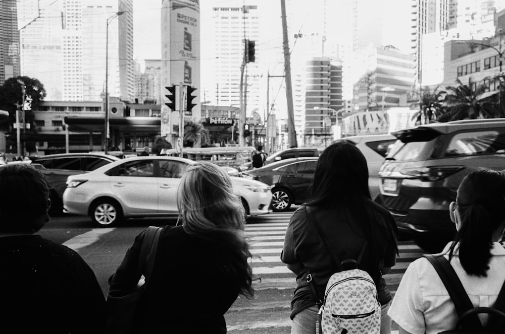 uma foto em preto e branco de pessoas esperando em uma faixa de pedestres