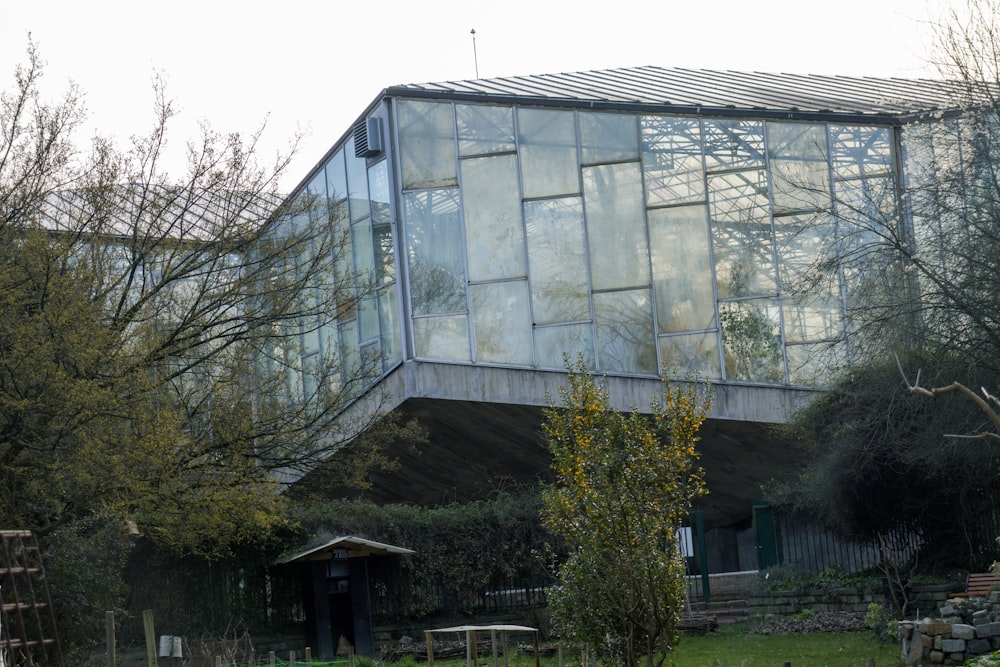 a large glass building sitting next to a lush green forest