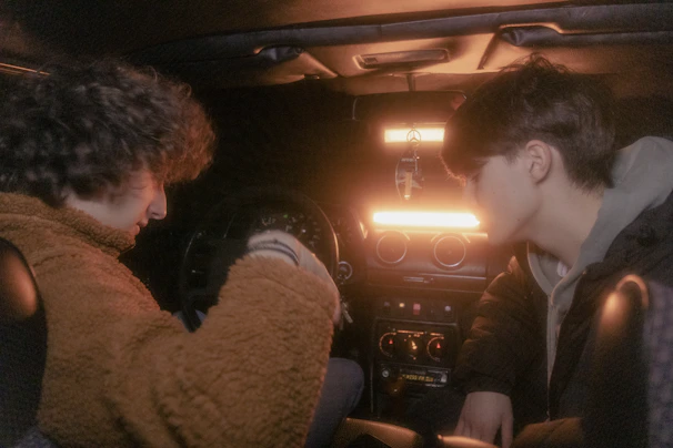 Two women sharing a comfortable ride in a softly lit car interior with touches of pink and beige.