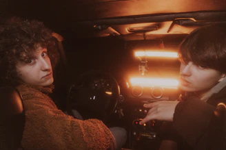 A driver confirming a safety code with a passenger inside a car at night.