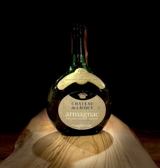 A close-up of a vintage Jean-Luc Pasquet Cognac bottle resting on a rustic wooden table with soft natural light highlighting its label.