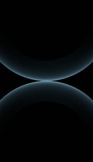 A minimalist design featuring two large, smooth, curved shapes that resemble abstract spheres. The color is a subtle gradient of dark blues against a black background, giving a futuristic and celestial appearance.