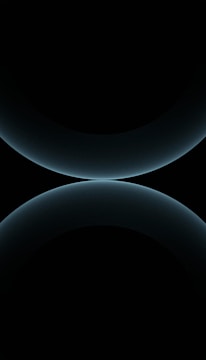 A minimalist design featuring two large, smooth, curved shapes that resemble abstract spheres. The color is a subtle gradient of dark blues against a black background, giving a futuristic and celestial appearance.