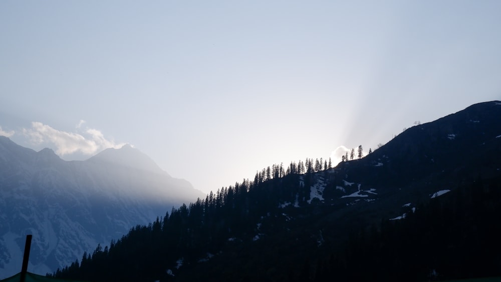 the sun shines through the clouds over the mountains