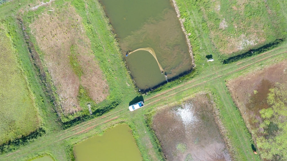an aerial view of a farm land with a pond