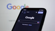 a close up of a cell phone with the google logo in the background