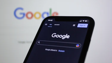 Dark-themed illustration showing a magnifying glass over a business location pin on a Google search page.