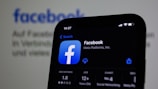 a close up of a cell phone with facebook on the screen